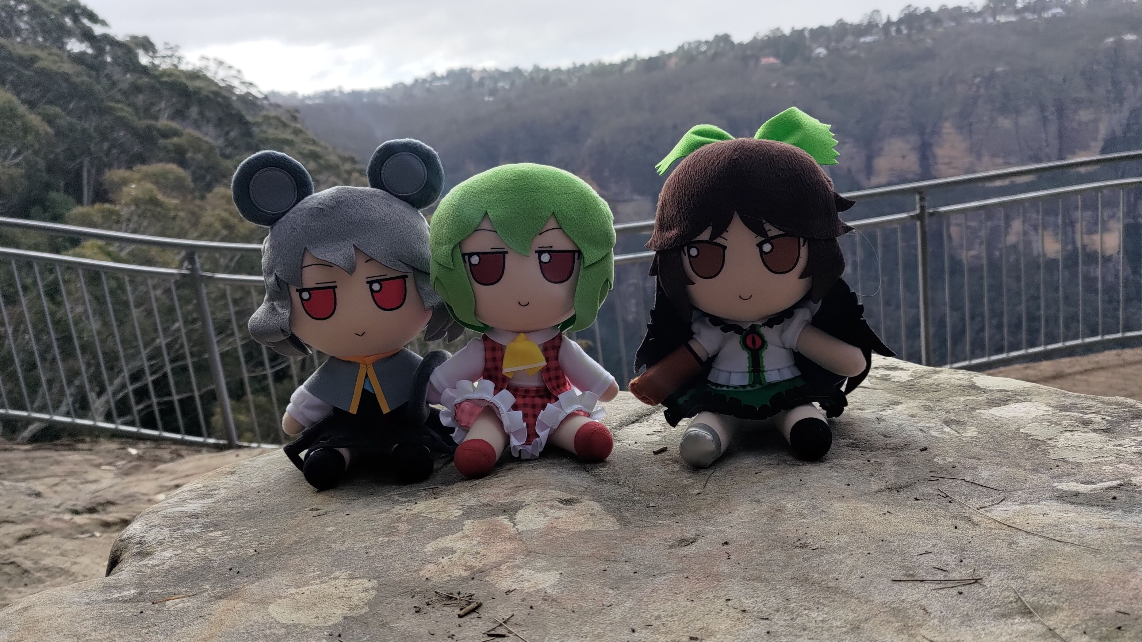 Three fumos sitting on a rock overlooking a canyon view.