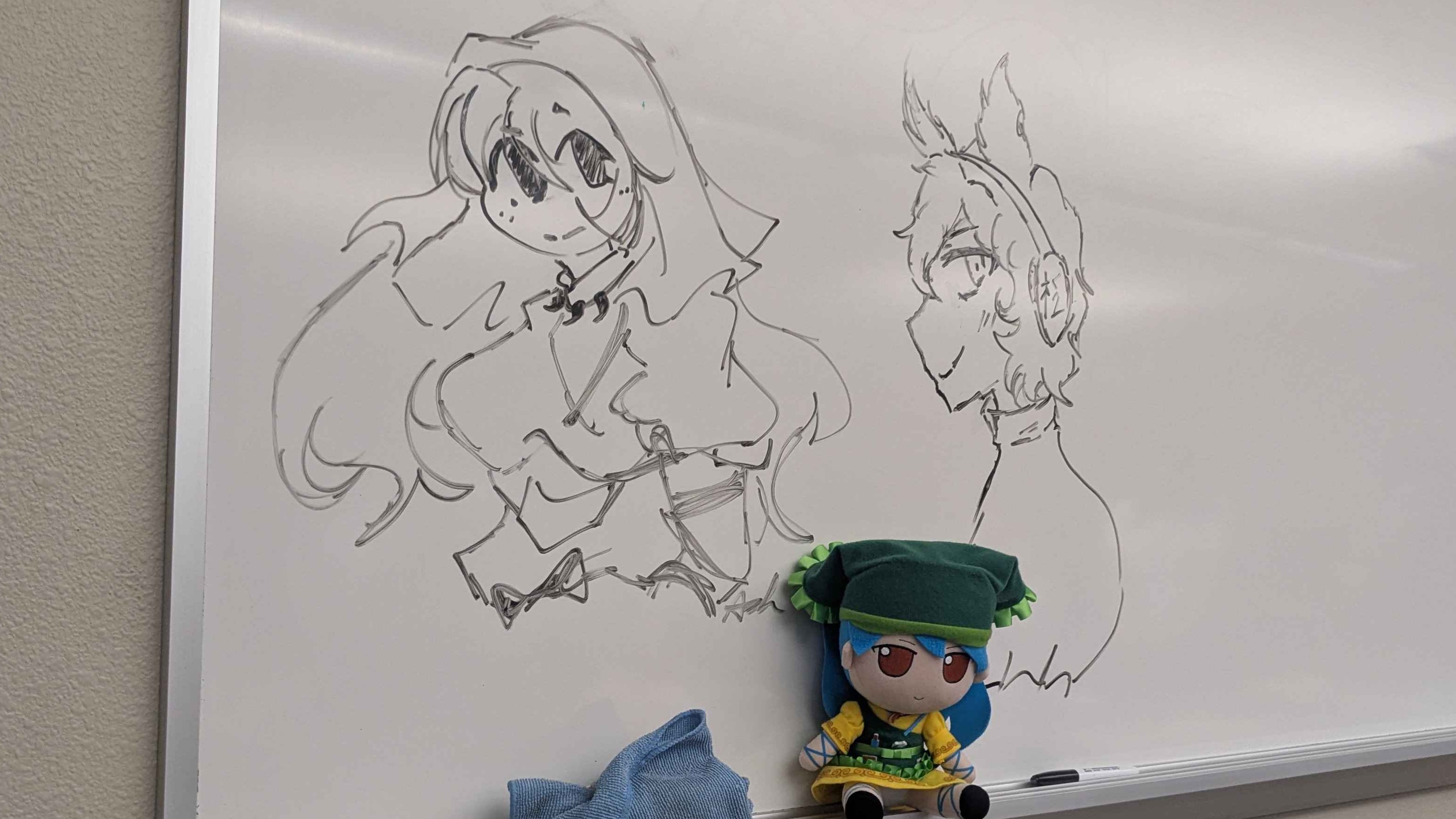 Photograph of two whiteboard drawings of Keiki and Miko, with a Keiki fumo sitting on the whiteboard.