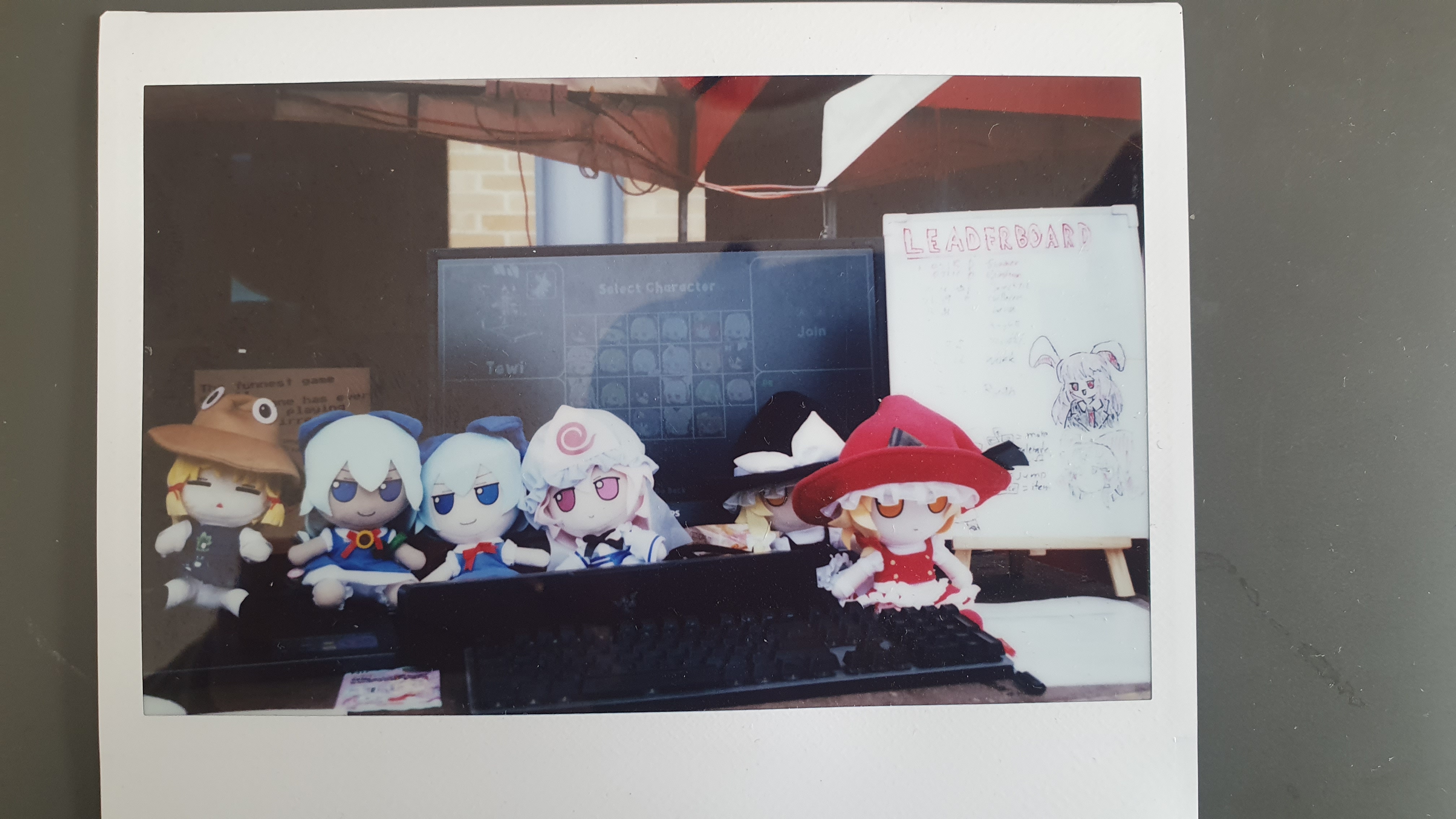 Polaroid photograph of fumo plush dolls in front of a computer.
